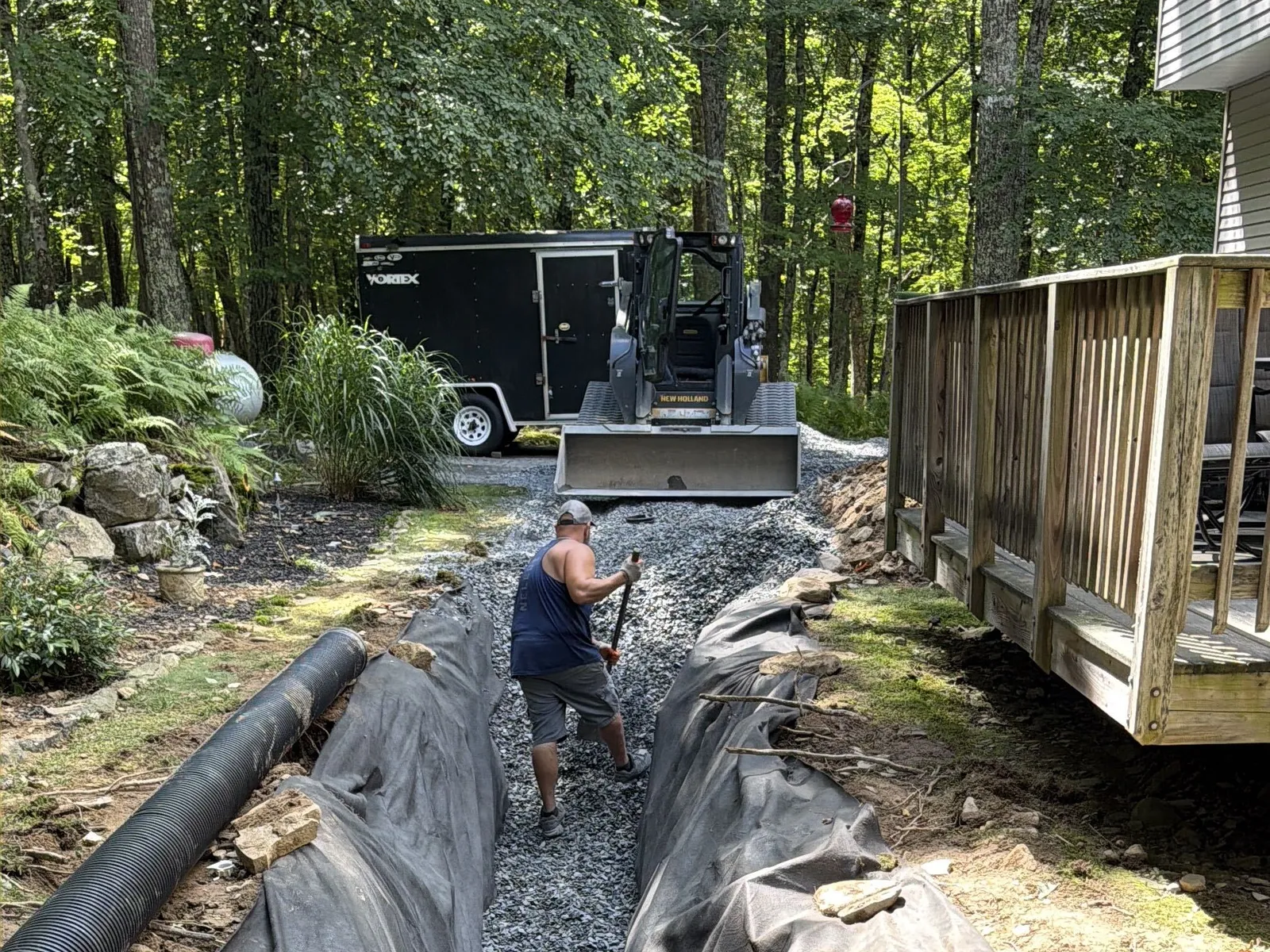 Filter fabric and stone laid in a drain trench beside a deck