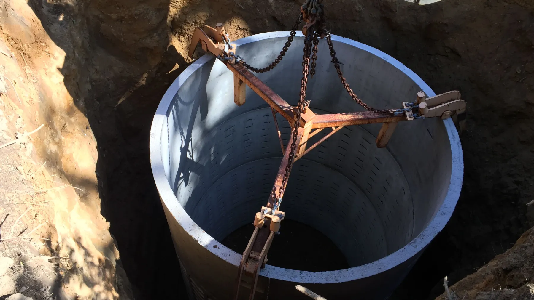 Precast concrete septic tank section being lowered into an excavation