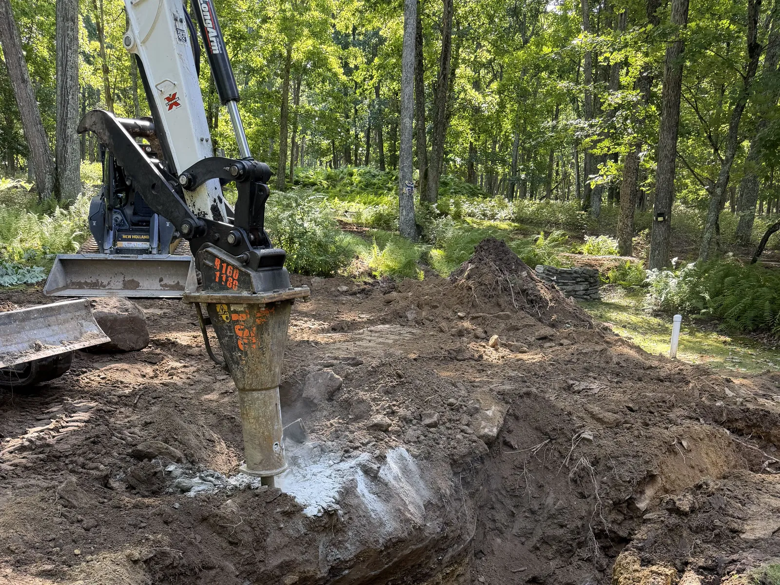 Hydraulic breaker on our skid steer breaking ledge along the trench line